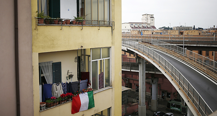 En italiensk flagga hänger från en balkong vid en tom väg