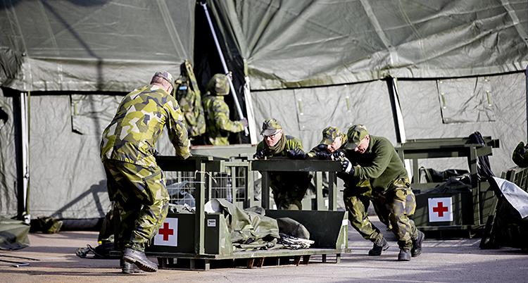 Soldater knuffar på en vagn med material