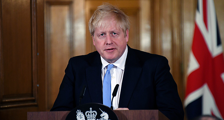 Boris Johnson står i en talarstol. Han pratar i en mikrofon. Han har ljust hår. Han har kostym och slips.