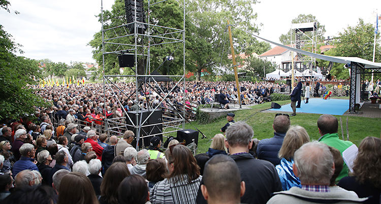 Många människor framför en scen i en grön park