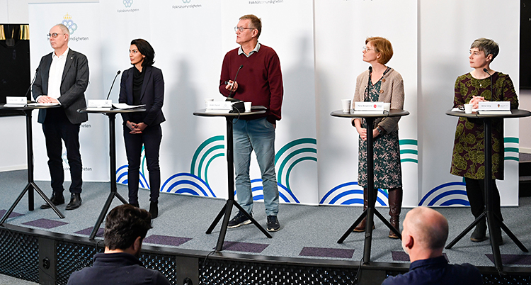 Bilden är från en presskonferens. Fem personer står på en scen. Det är tre kvinnor och två män. De har varsin mikrofon.