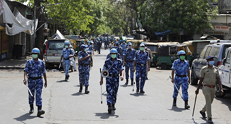 Många poliser med käppar går längs en gata i Indien