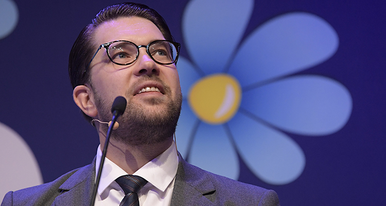 Jimmie åkesson tittar upp. Bakom honom syns SD:s blå blomma.