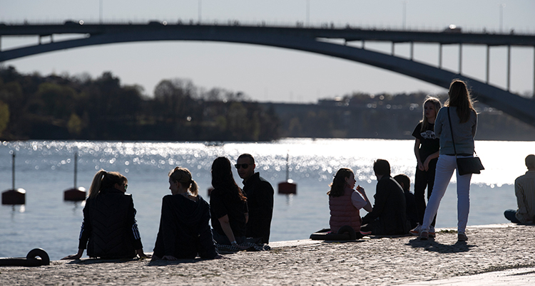 en varm sommardag vid havet. Folk sitter på en strand.