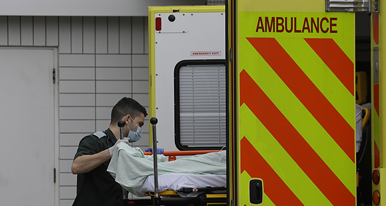 En patient lyfts ur ambulansen. En sköterska håller i britsen.