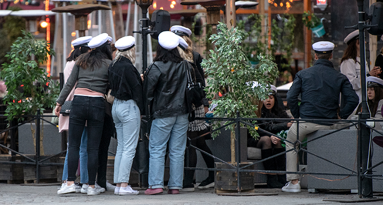 Några ungdomar med studentmössor står utanför en restaurang