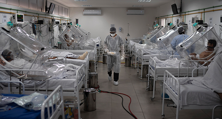 En sal på ett sjukhus med massor av sängar, patienter och olika slangar och maskiner.
