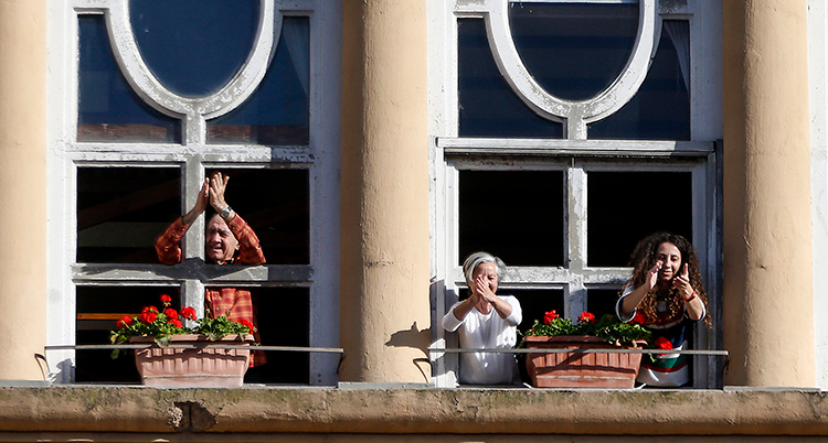 Tre människor står på en balkong. De klappar händerna.