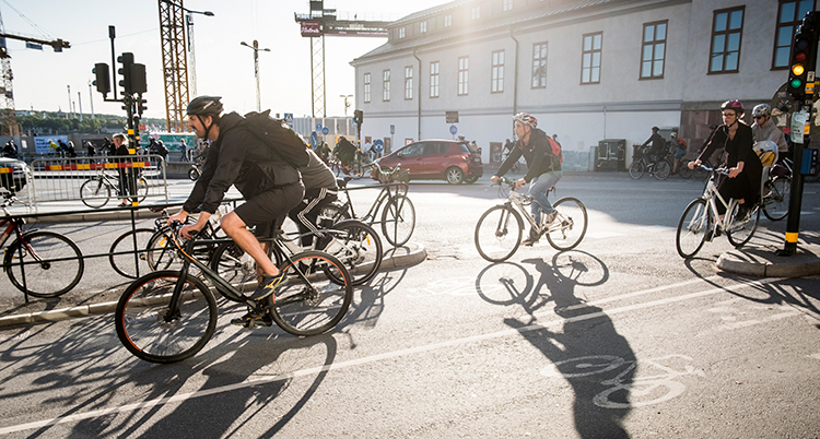 Cyklister vid slussen i Stockholm. Solen skiner. De verkar köra snabbt.