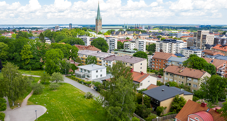 En flygbild över Linköping. I bakgrunden syns domkyrkan. Längst fram en gata utan trafik. Låga hus är på ena sidan och en park på den andra.