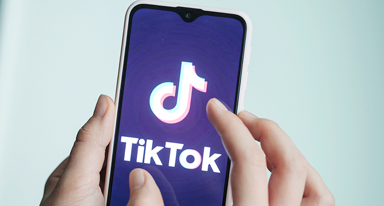 En bild på en hand som håller upp en mobiltelefon där man ser appen Tiktok.
