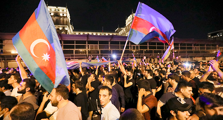 Många demonstrerar i Azerbajdzjan. Två personer håller upp landets flagga.