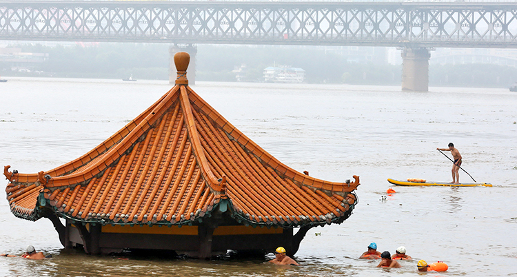 Människor simmar förbi en översvämmad byggnad i Yangtzefloden i Kina.