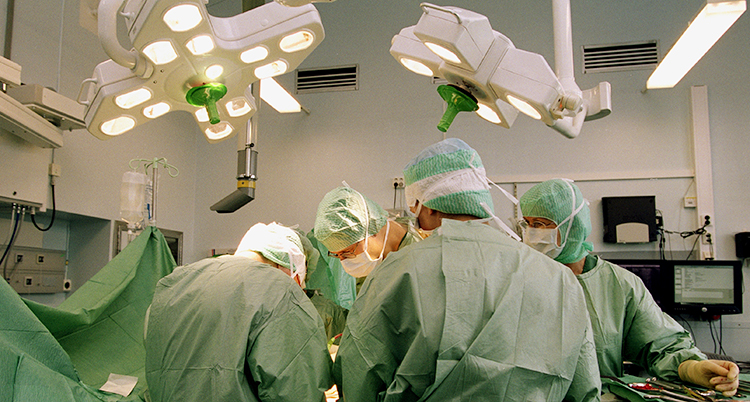 En operation på Södersjukhuset. Personal i gröna kläder lutar sig över bordet där personen ligger.