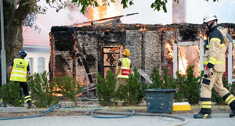 Räddningstjänsten jobbar med att släcka branden i en byggnad av trä.