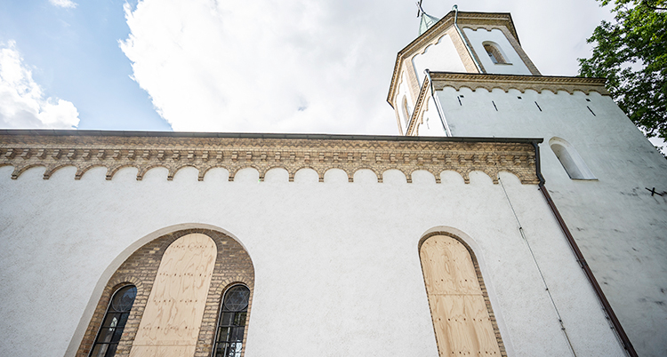 Den vita kyrkan har fått träskivor för fönstren.