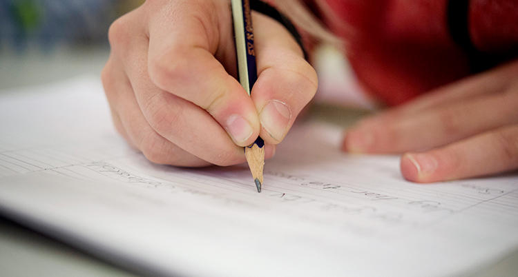 En elev skriver med en blyertspenna.
