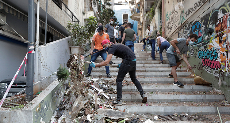 Flera människor röjer upp på en förstörd gata i Beirut.