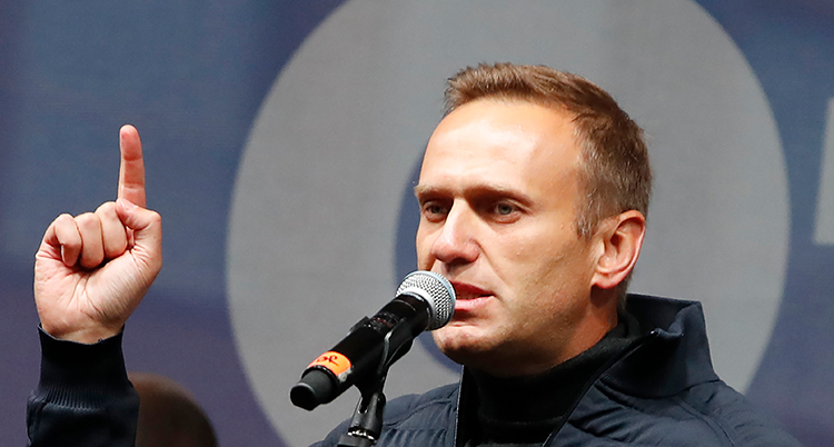 Navalnyj talar i en mikrofon. Han håller upp ett finger som om han varnar någon.