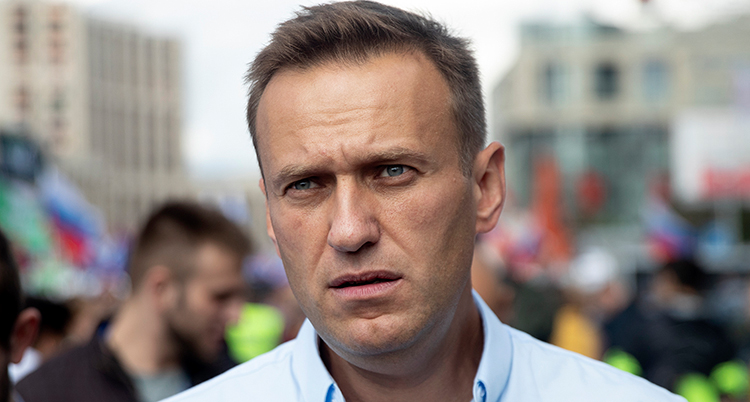 Aleksej Navalnyj står utomhus i blå skjorta. Han ser allvarlig ut.