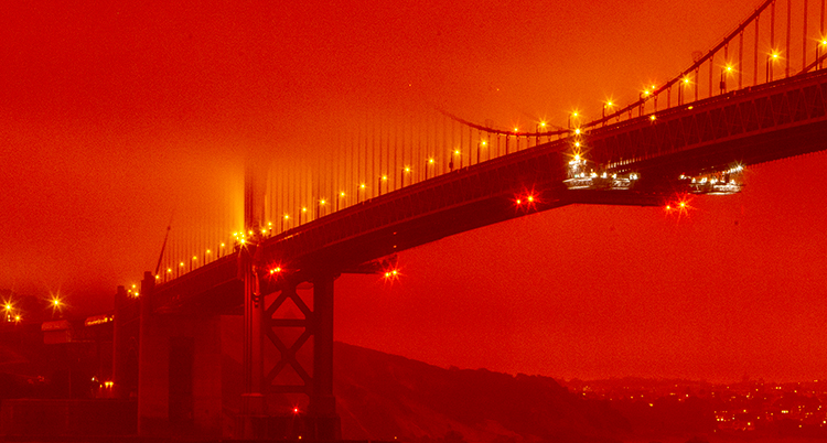 Bron är lång och har flera lampor på sig. Ovanför syns en mörk och orange himmel.