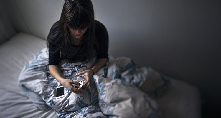 en kvinna i en säng med en karta med piller och ett glas vatten.