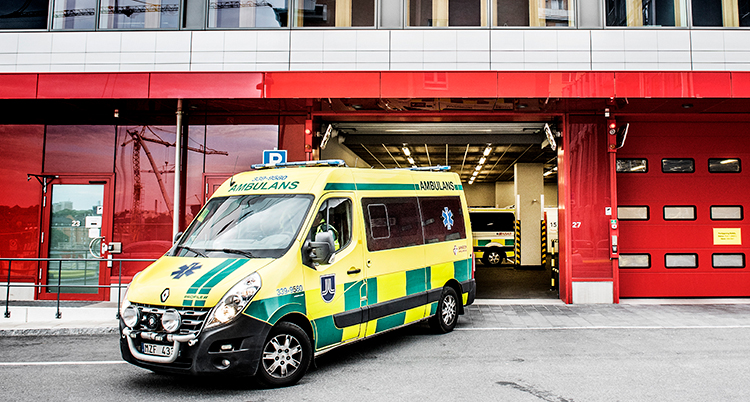 En ambulans står utanför röda portar.