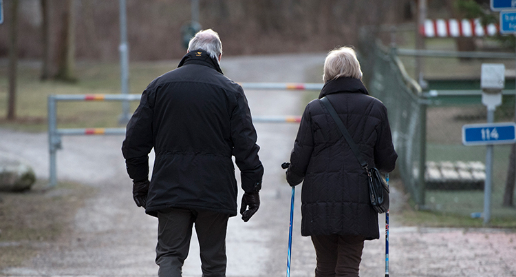 Tv å gamla personer är ute och går på en väg. En dem har stavar i händerna.