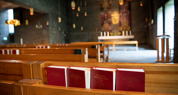 Psalmböcker som står på en hylla i en bänk i en kyrka