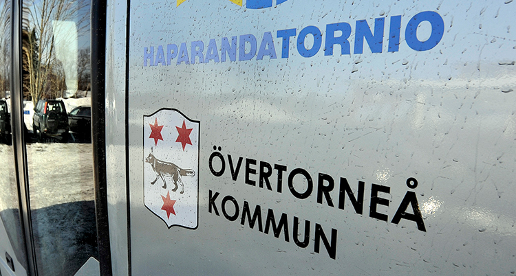 En nära tagen bild på en sida av en buss där det står Övertorneå kommun.