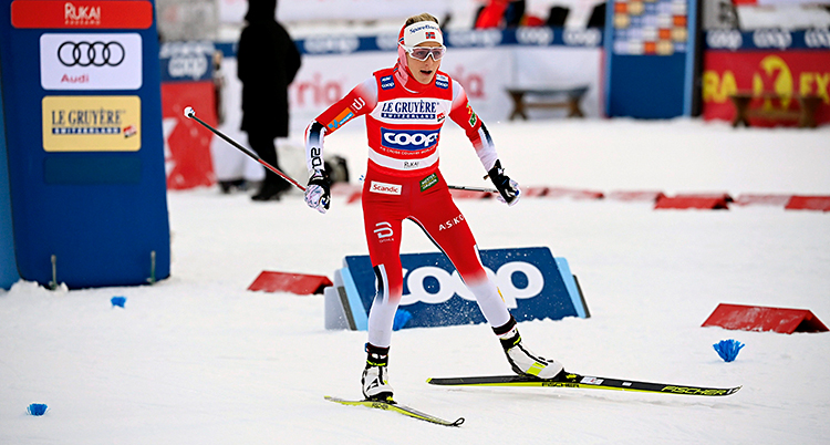 Therese Johaug har precis startat en tävling. Hon åker skidor på snön. Hon har en röd och vit dräkt.