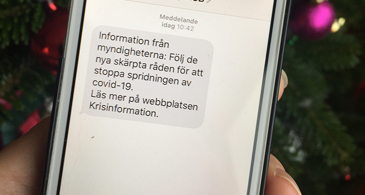 en bild på mobil med sms: information från myndigheterna: Följ de nya skärpta råden för att stoppa spridningen av covid-1+. Läs mer på webbplatsen Krisinformation.