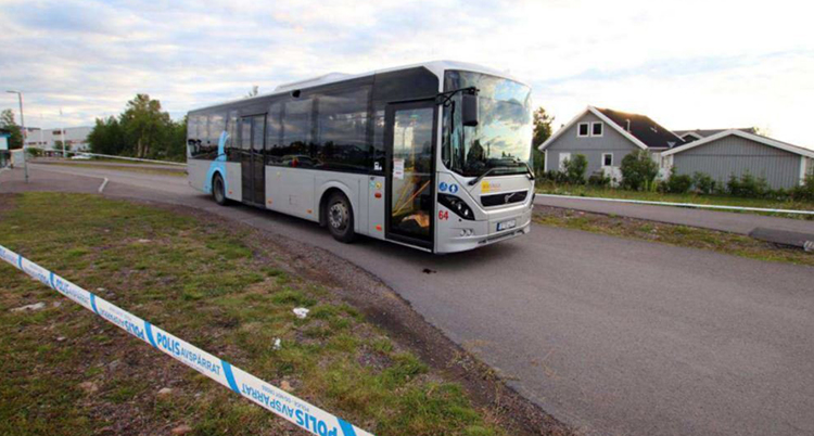 Polisens avspärrningsband framför en vit buss som står på en landsväg