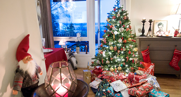Ett vardagsrum med julpynt, paket och en julgran