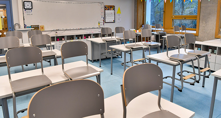 Stolar är upphängda på bänkarna i ett tomt klassrum