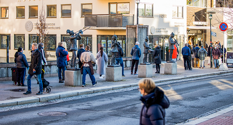 En lång kö på en trottoar till en butik.