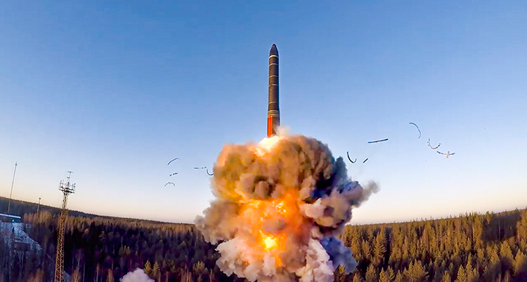 En smal lång raket ses lämna marken i ett eldmoln och gå rakt uppåt mot den blå himlen.