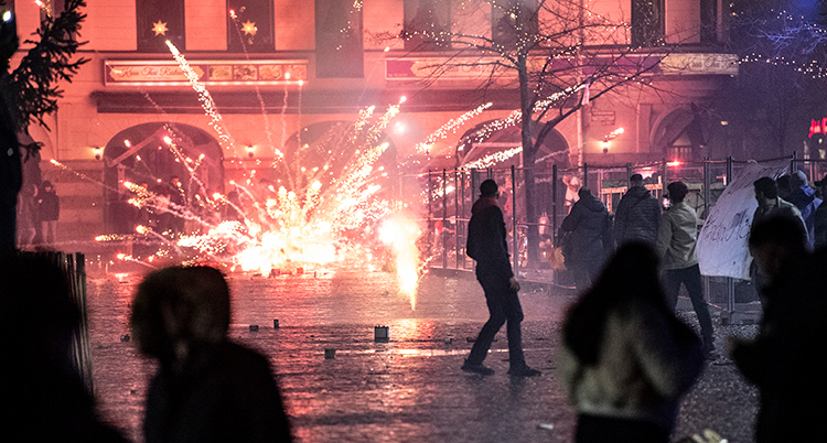 En raket exploderar. Gnistor åker åt alla håll. Människor står göra.