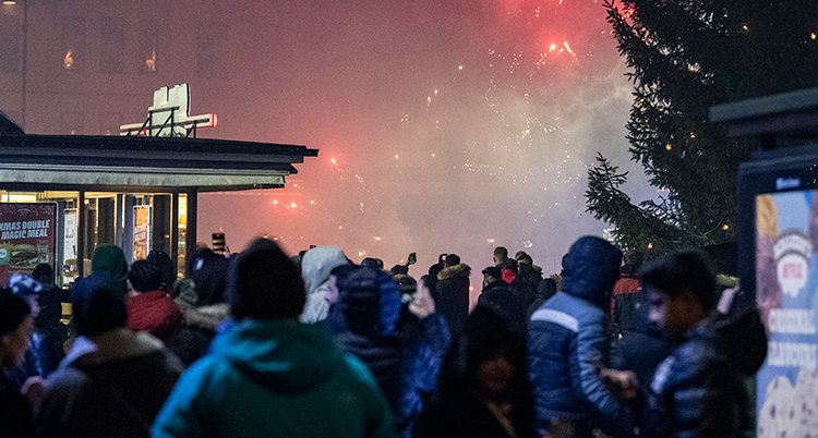 Många människor som står nära varandra på ett torg med rök i himlen