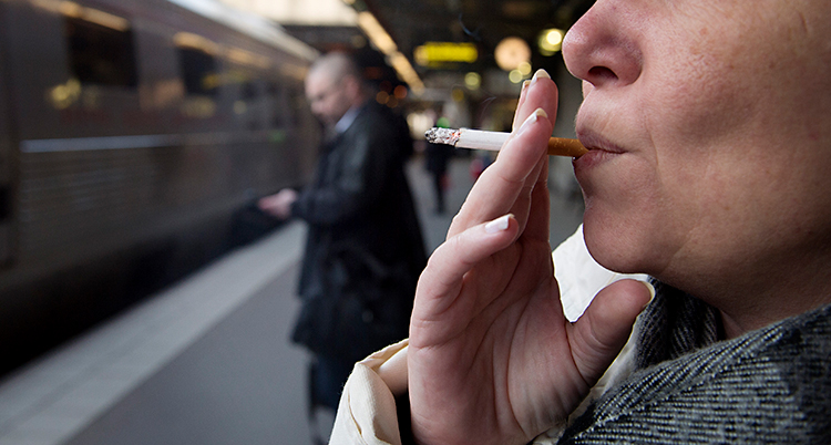 Det är en närbild på en kvinna som röker en cigarett. Bilden börjar vid näsan så vi ser inte hennes ögon. Hon står på en perrong. Där finns ett tåg.