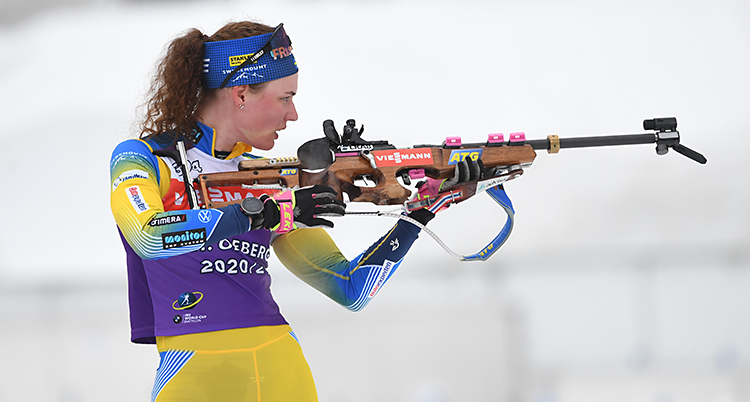 Hanna Öberg står med sitt gevär. Hon ska skjuta. Hon har på sig Sveriges dräkt i gult.