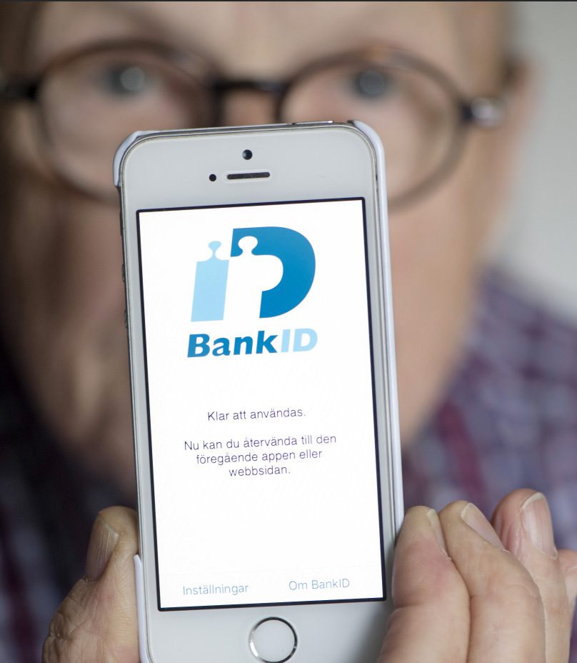 En person visar sin mobil. På skärmen står det bank-id med blå bokstäver.