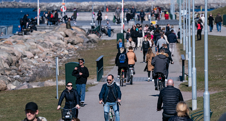 Människor cyklar och går på en cykel- och gångbana intill vattnet.