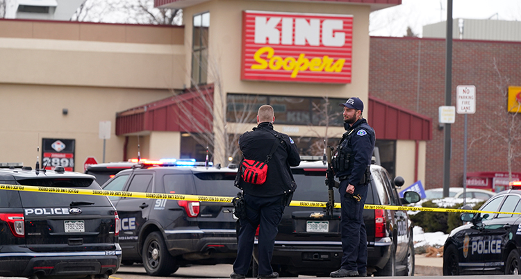Två poliser med vapen står utanför en stor affär. På en skylt står det King Soopers.