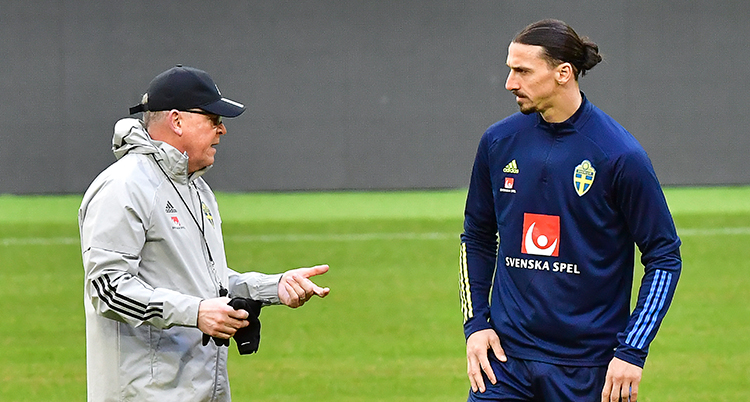 Janne Andersson i grå jacka och keps pratar med Zlatan som har landslagets blå tröja.