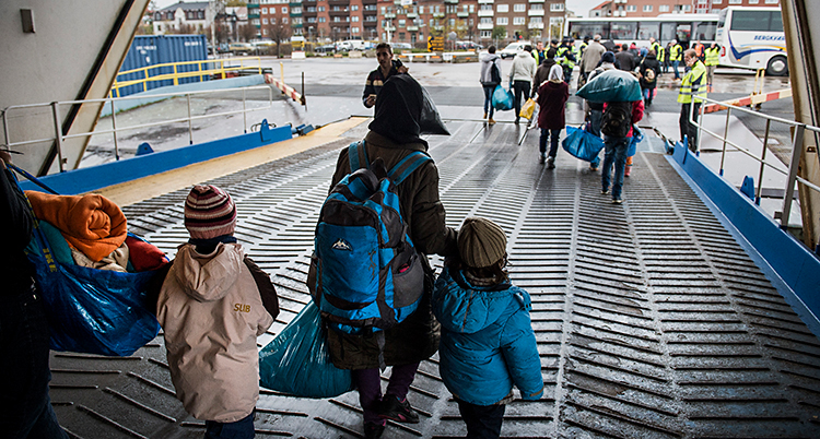 Bilden är från hamnen i Trelleborg. Några personer går av en båt. Det är några vuxna och några barn. Vi ser dem bakifrån.