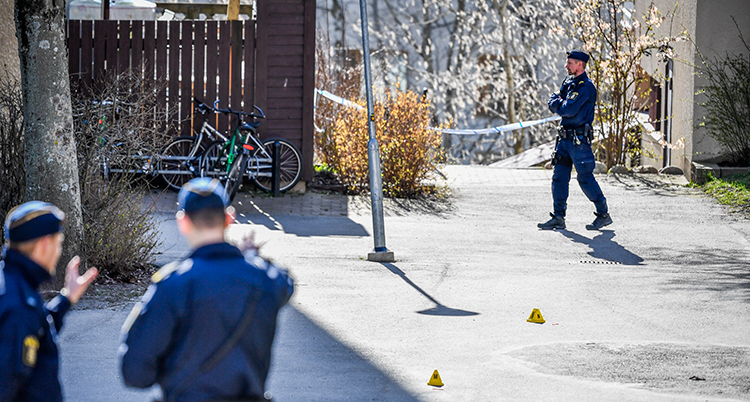 En gata. Tre poliser syns på bild. Några cyklar syns i ett hörn.