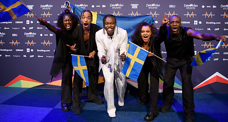 Fem personer tittar in i kameran och jublar. Tusse står i mitten. De ha svenska flaggor.