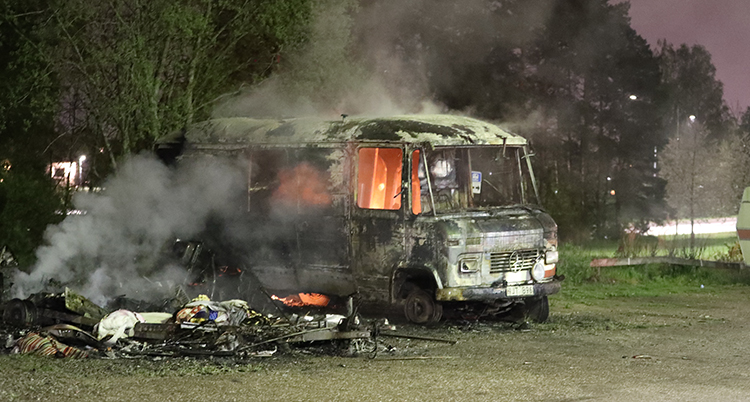 En mindre buss brinner. Det mesta är utbränt men inne i bussen brinner det fortfarande. Foto: TT