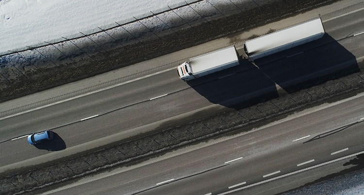 En lastbil och en bil kör på en motorväg. Bilden är tagen ovanifrån.